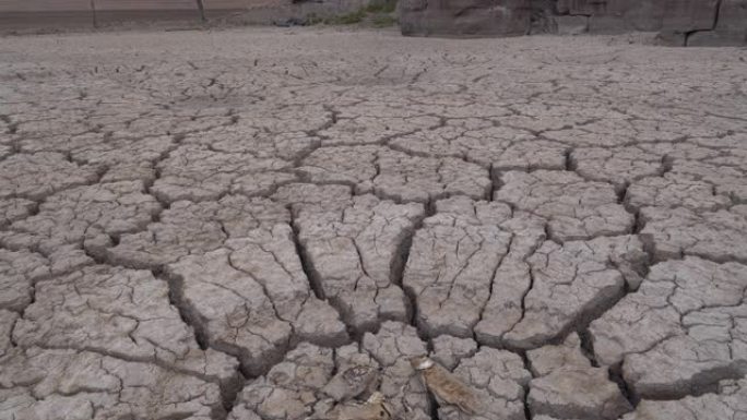 由于气候变化和全球变暖造成的干旱，位于干燥大坝破裂的泥浆表面上的死鱼的4k特写倾斜视图