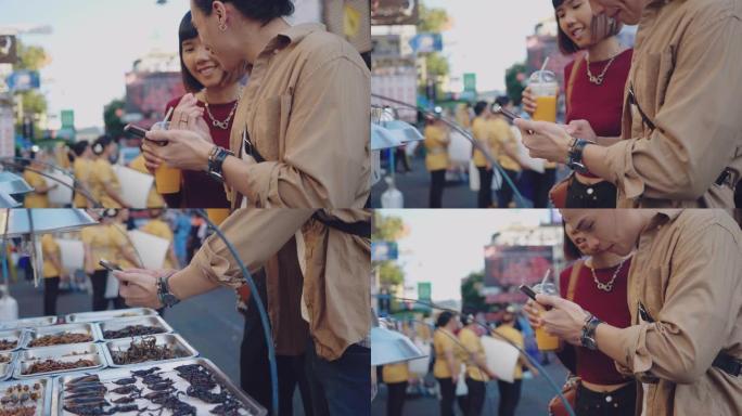 年轻的亚洲夫妇在曼谷考山路的街头食品市场购买被解雇的昆虫