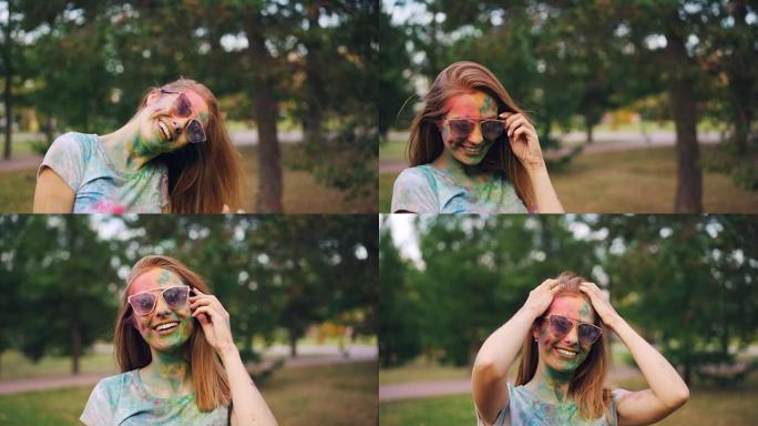 胡里节上漂亮的女孩的肖像，脸上涂着脸，看着相机，带着迷人的微笑，抚摸着她的头发和太阳镜。乐趣和文化概