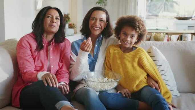 快乐三代女家庭组坐在一起看电视笑着一起吃爆米花