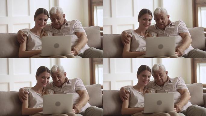 80年代快乐的男人拥抱成年女儿，看着电脑屏幕。