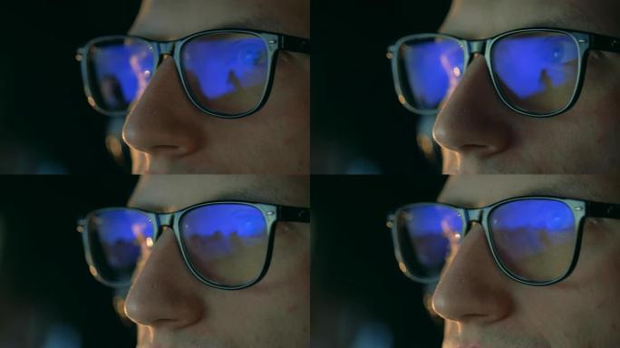 一位戴着眼镜的玩家看着显示器，特写镜头。
