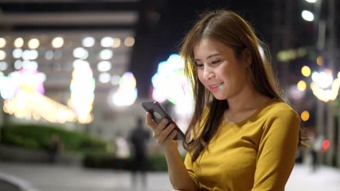 晚上在城市使用智能手机的女人