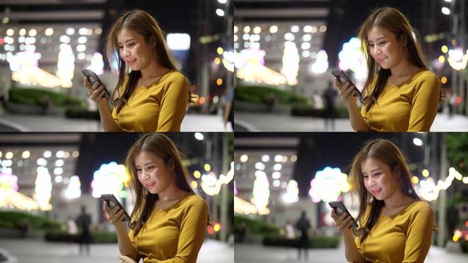 晚上在城市使用智能手机的女人