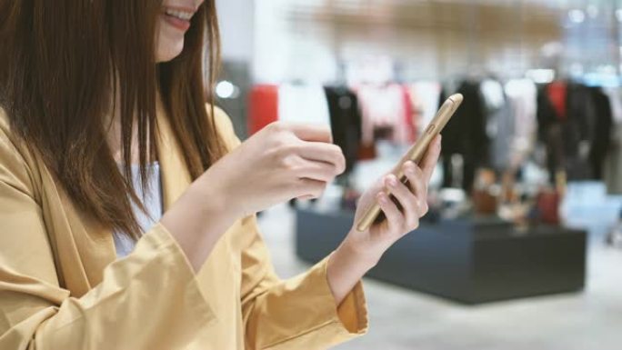 4k镜头亚洲女性使用信用卡和手机在线购物的场景百货商店无现金，科技钱包和在线支付概念，信用卡模型