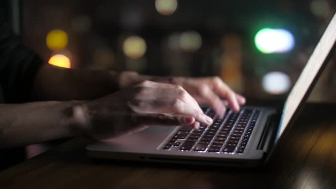 男人的手在晚上在笔记本电脑上打字