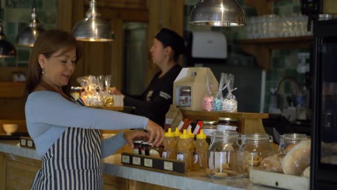 一家面包店开朗的女企业主，用美味的产品安排柜台展示
