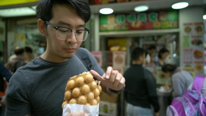 游客吃香港特色小吃鸡蛋华夫饼/泡泡华夫饼