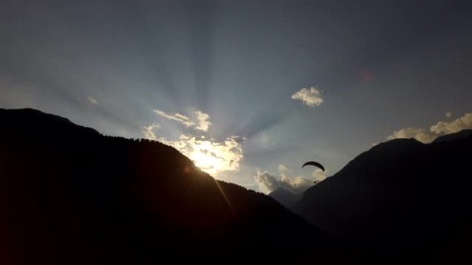 日落时在山上滑翔伞的人的剪影。