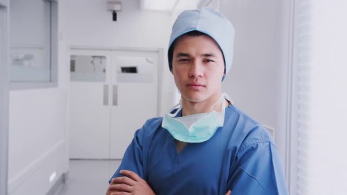 站在医院走廊上戴着磨砂膏和口罩的男性外科医生的肖像