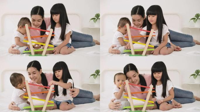 幸福的家庭年轻妈妈保姆和可爱的小孩女儿在床上玩木头玩具游戏。
