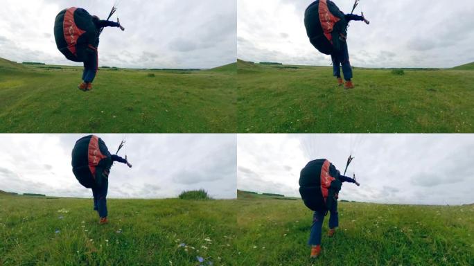 运动员驾驶滑翔伞，降落在田野上。