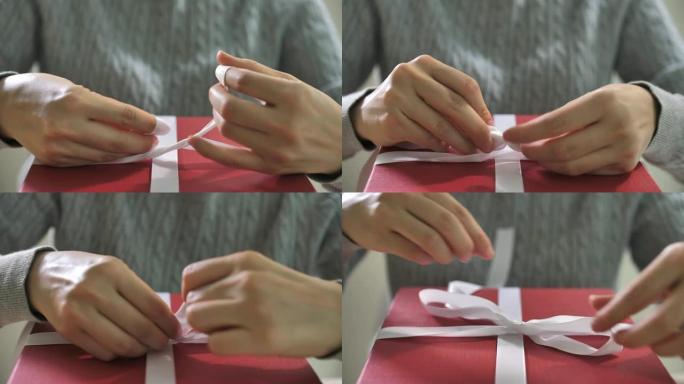 女人在家里的礼品盒上绑上包裹白色丝带，特写