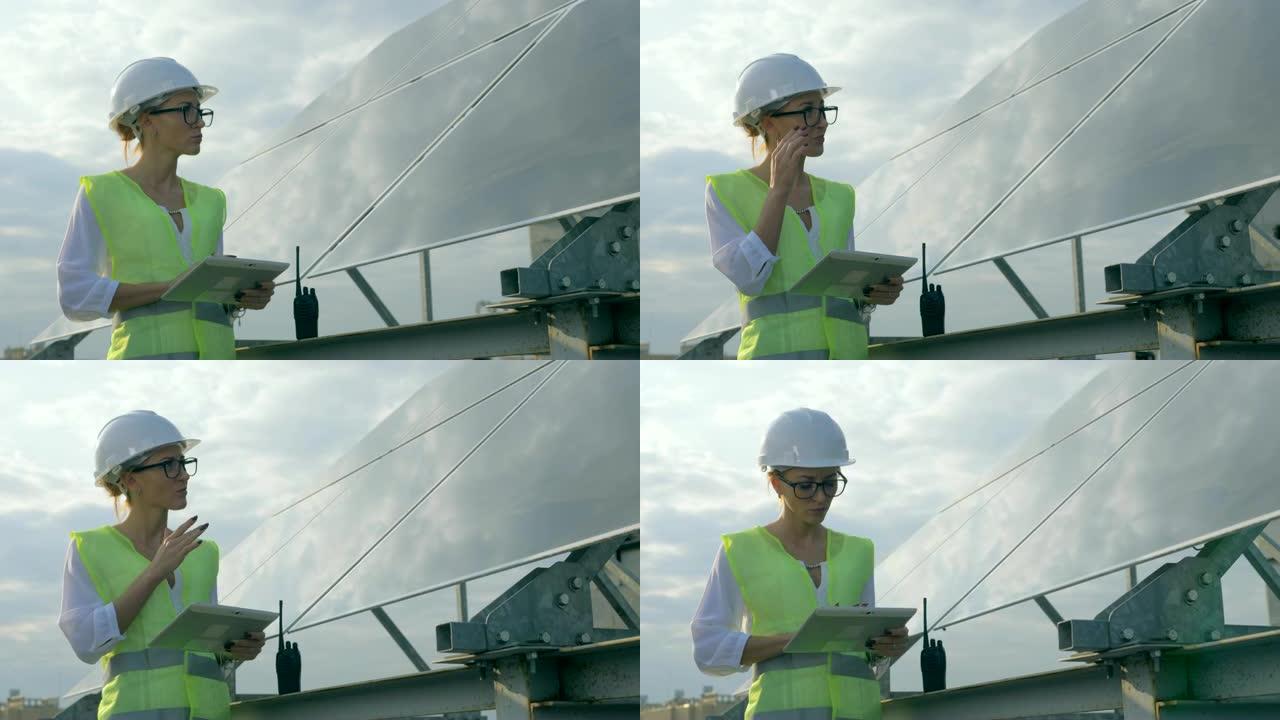 女建造师正站在太阳能电池附近并使用平板电脑