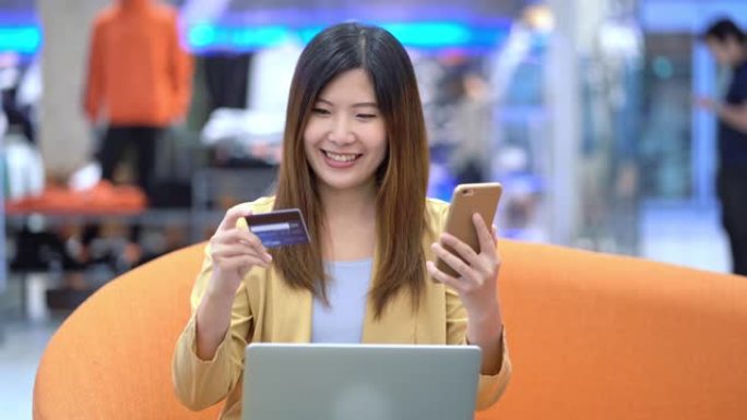 4k镜头亚洲女性使用信用卡和手机在线购物的场景百货商店无现金