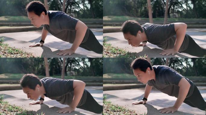亚洲男子通过俯卧撑和听音乐锻炼身体