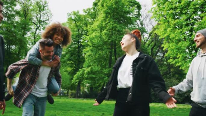 在阳光明媚的日子里，一群不同种族的年轻朋友在绿色的城市公园里一起玩耍