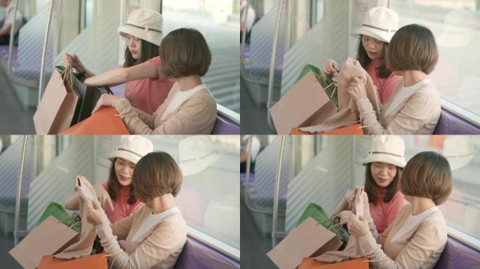 两名年轻的亚洲女性在乘坐地铁慢动作时在购物袋中展示新购买的商品