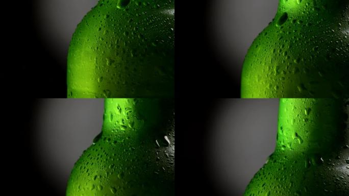 冷却的湿绿色啤酒瓶在黑色和灰色背景下旋转。特写镜头，4K