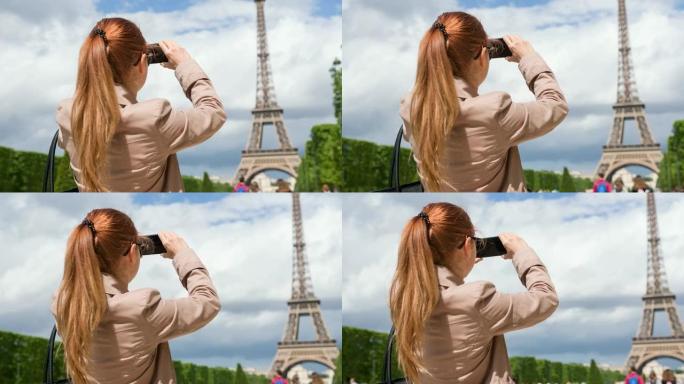 战神花园中的女人用智能手机为埃菲尔铁塔拍照