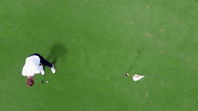 人们在绿色球场打高尔夫球，将球打入洞中。