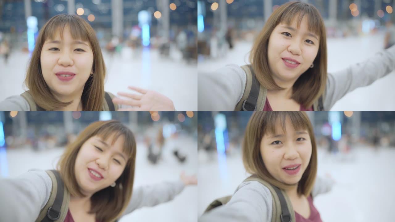 慢动作-年轻的亚洲背包客博主妇女在等待飞行时使用相机制作vlog视频，女性站在国际机场的候机楼大厅。