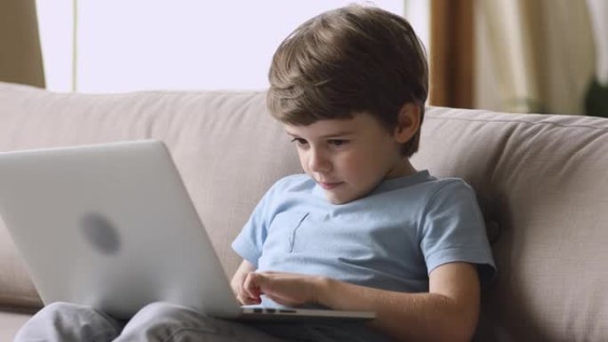沉迷于技术快乐的小孩在笔记本电脑上玩游戏。
