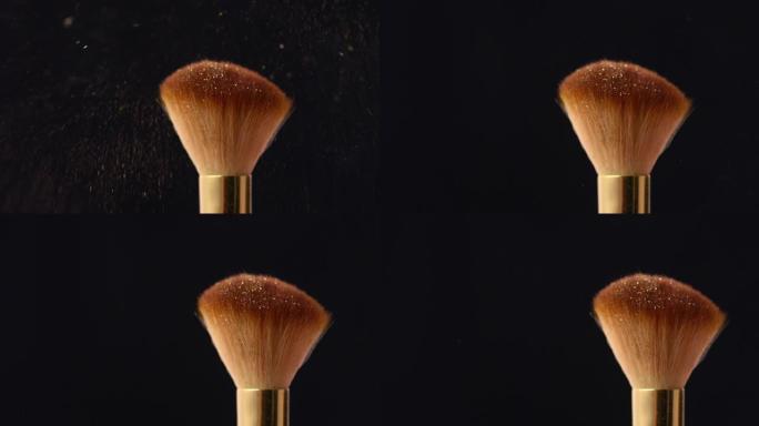 从黑色背景上的化妆刷中清除金色微光粉