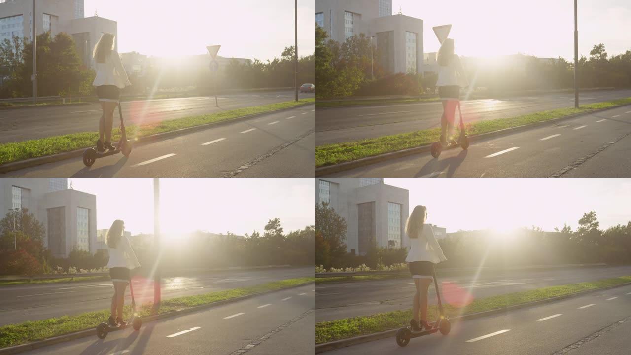 镜头耀斑: 无法识别的女商人在日出时骑着电动踏板车上班。