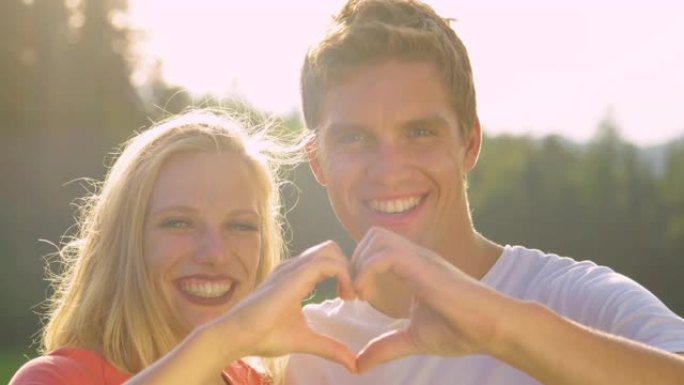 肖像: 严肃的夫妇用手指对着镜头微笑，形成心形。