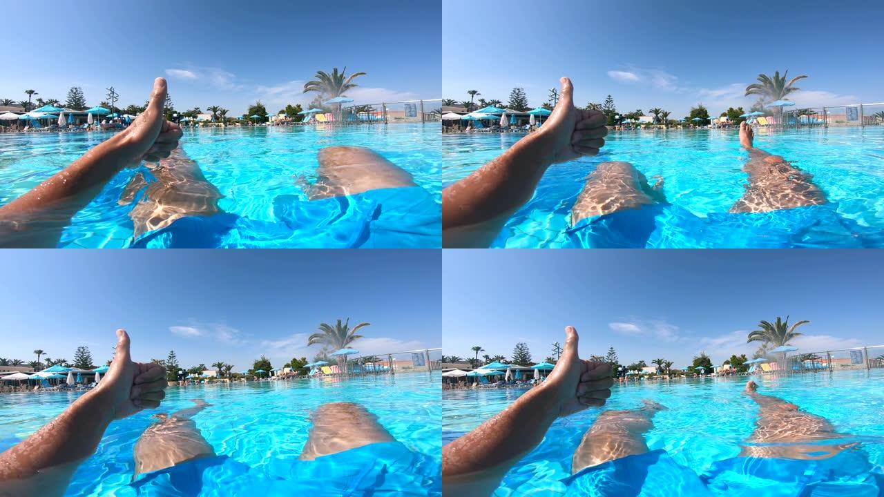 人坐在酒店附近的游泳池里竖起大拇指。暑假概念。