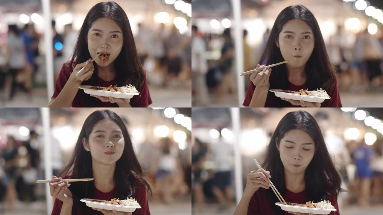 亚洲年轻女子在泰国曼谷旅行，美丽的女性在考山路散步和吃泰国菜感到快乐。妇女旅游吃街头食品泰国概念。慢