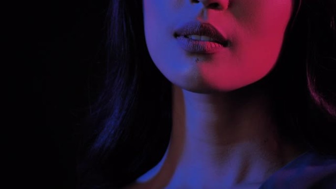 在紫外线黑光下，黑色背景上美丽性感女人的性感肖像的精彩视频。富有表现力的面部表情。美容和水疗。美丽的