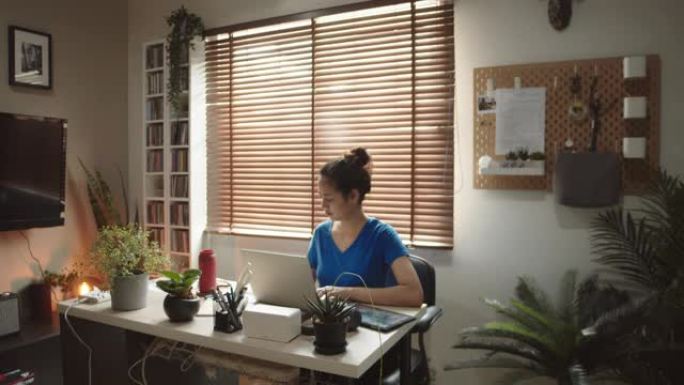 亚洲女性在家里使用笔记本电脑而苦苦挣扎。
