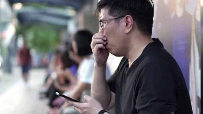 亚洲年轻人在污染中等待公共交通工具时使用手机