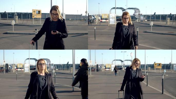 女商人在阳光明媚的机场人行道上使用智能手机