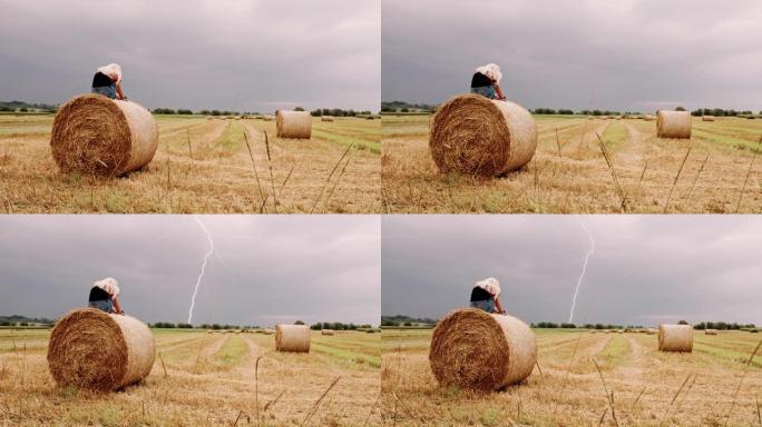 DS孤独的女人坐在草捆上，闪电划过天空