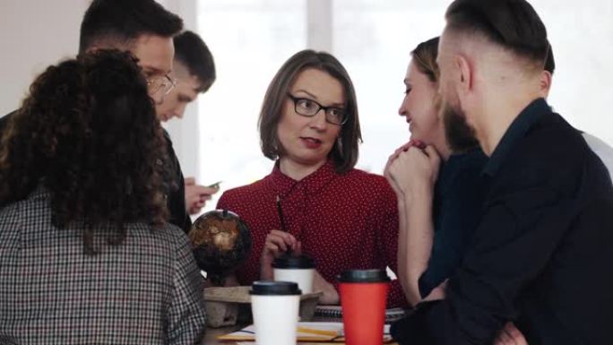 快乐的中年白人领导人商界女性在与同事在休息期间与咖啡。