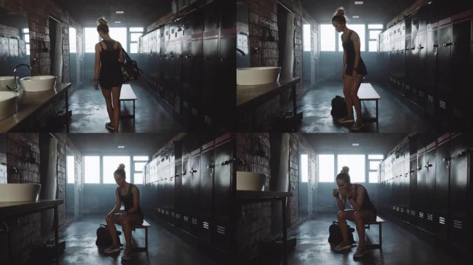 摄像机跟随欧洲运动女子进入黑暗的健身房更衣室，坐着感到疲倦和沮丧的慢动作。