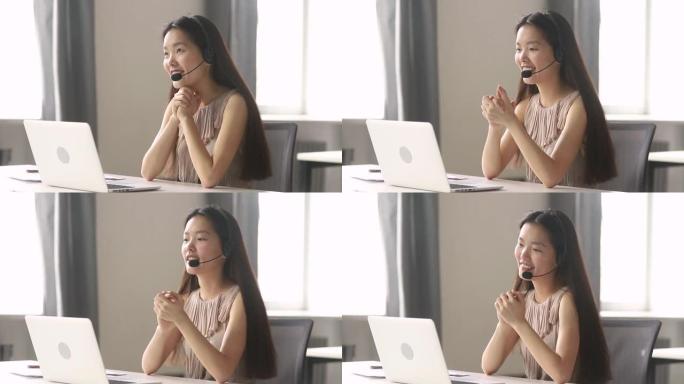 微笑的亚洲女商人戴着无线耳机在笔记本电脑上通话视频
