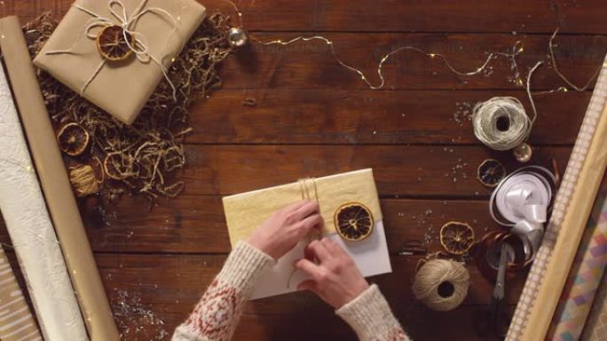 用干橙片和绳子装饰圣诞礼品盒的女人