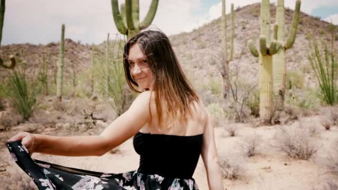 慢动作相机跟随年轻的微笑快乐的旅游女人，在史诗般的阳光明媚的仙人掌沙漠美国行走。