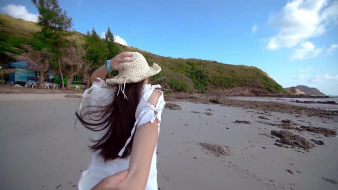 那个女孩握着男性的手，在热带海滩上奔跑。暑假或假期