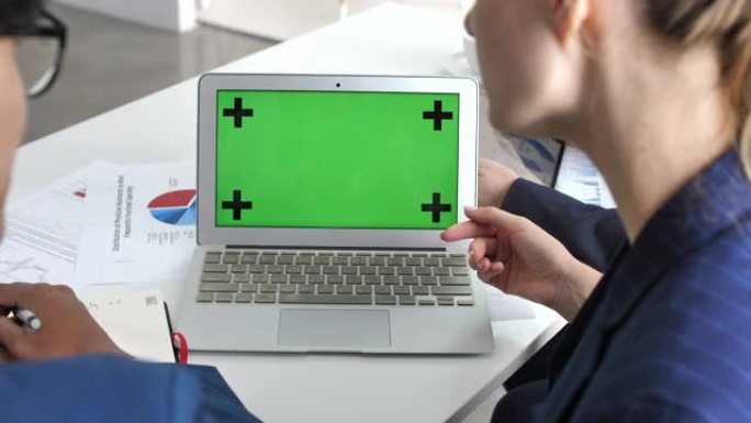 两名商务人士与笔记本电脑绿屏交谈