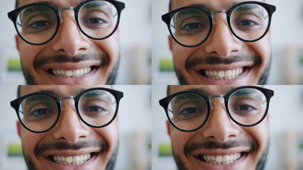 戴眼镜的英俊阿拉伯男人的特写肖像看着相机微笑