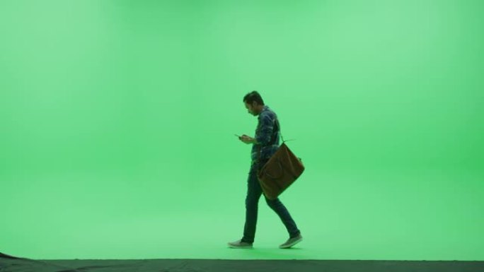 绿屏工作室: 强壮的印度男子穿着便服和行李袋，使用智能手机设备，处理业务，与女友交谈穿过色度钥匙室。