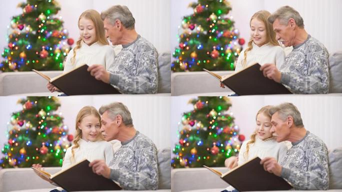 快乐老人在圣诞树旁与女孩一起看相册