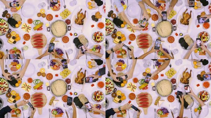 年轻朋友的特写镜头用智能手机将照片放在桌子上的食物上。在社交媒体上拍照，并在意大利美食，香肠和沙拉，