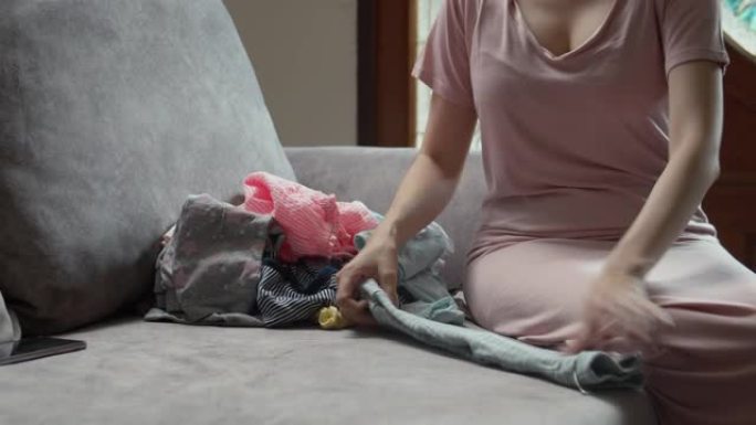 妈妈坐在沙发上折叠婴儿衣服