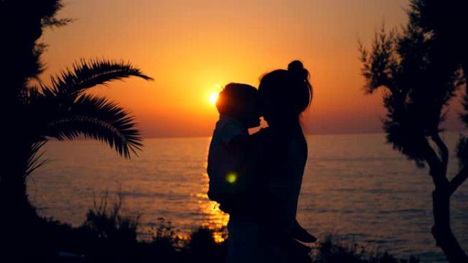 家庭，爱情，温柔的概念。母亲和儿子在日落背景下拥抱。